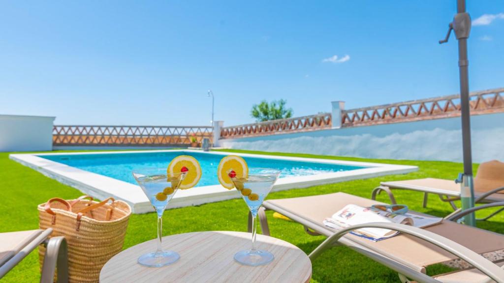 two glasses on a table next to a swimming pool at Rubito el Olmo Villanueva de la Concepción by Ruralidays in Villanueva de la Concepción