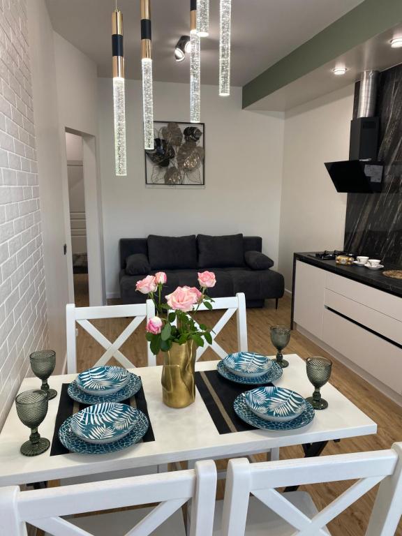 a living room with a table with plates and flowers at Авторський ремонт Апартаменти біля Щасливого,поруч озеро in Rivne