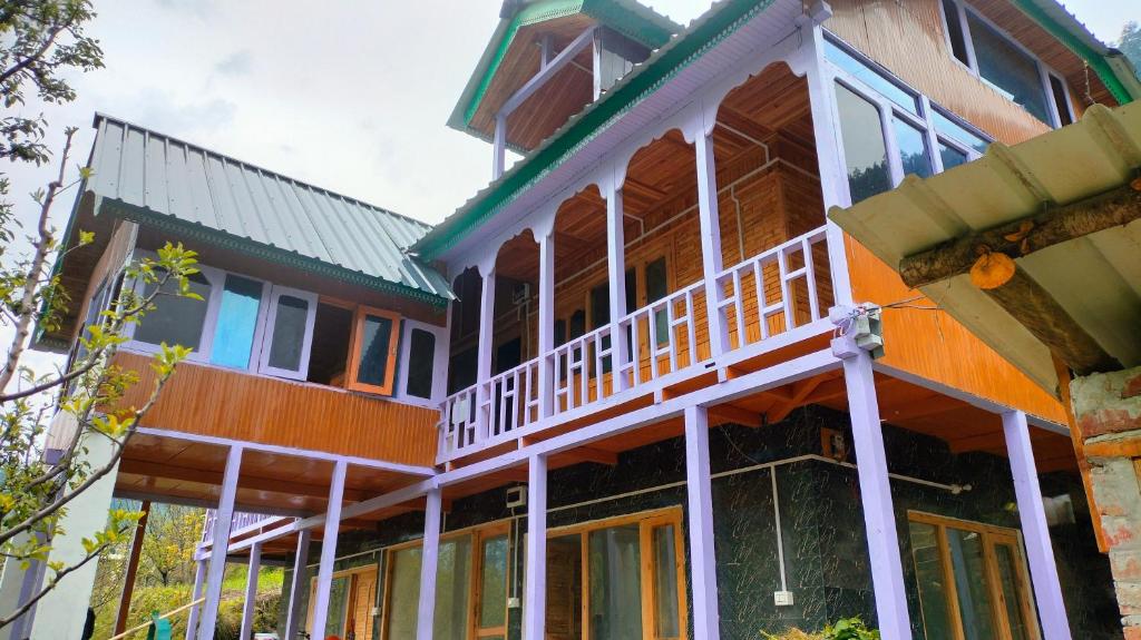 a large house with a balcony on top of it at Mother's eco lodge in Jibhi