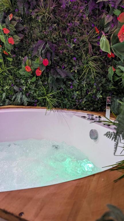 une baignoire devant un buisson avec des fleurs dans l'établissement SUITE Roch'amore troglodyte Romantique et Unique, à La Garde