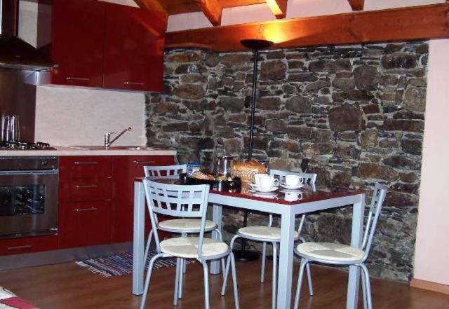a kitchen with a table and chairs and a stone wall at Roccetta Fiorita in Pettenasco