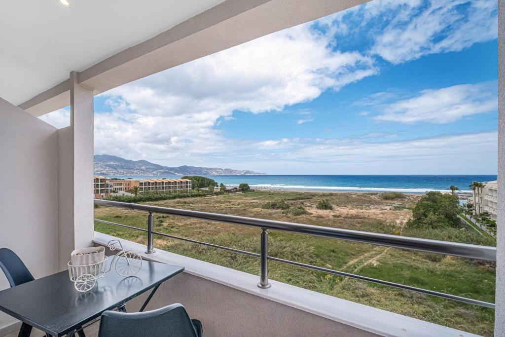 een balkon met een tafel en stoelen en uitzicht op de oceaan bij Grande Mare with Sea view in Amoudara Herakliou