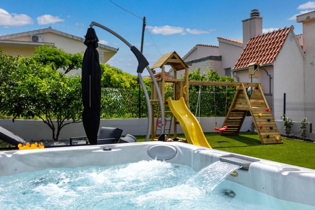 a backyard pool with a hot tub and a playground at Apartments Solmar in Podstrana