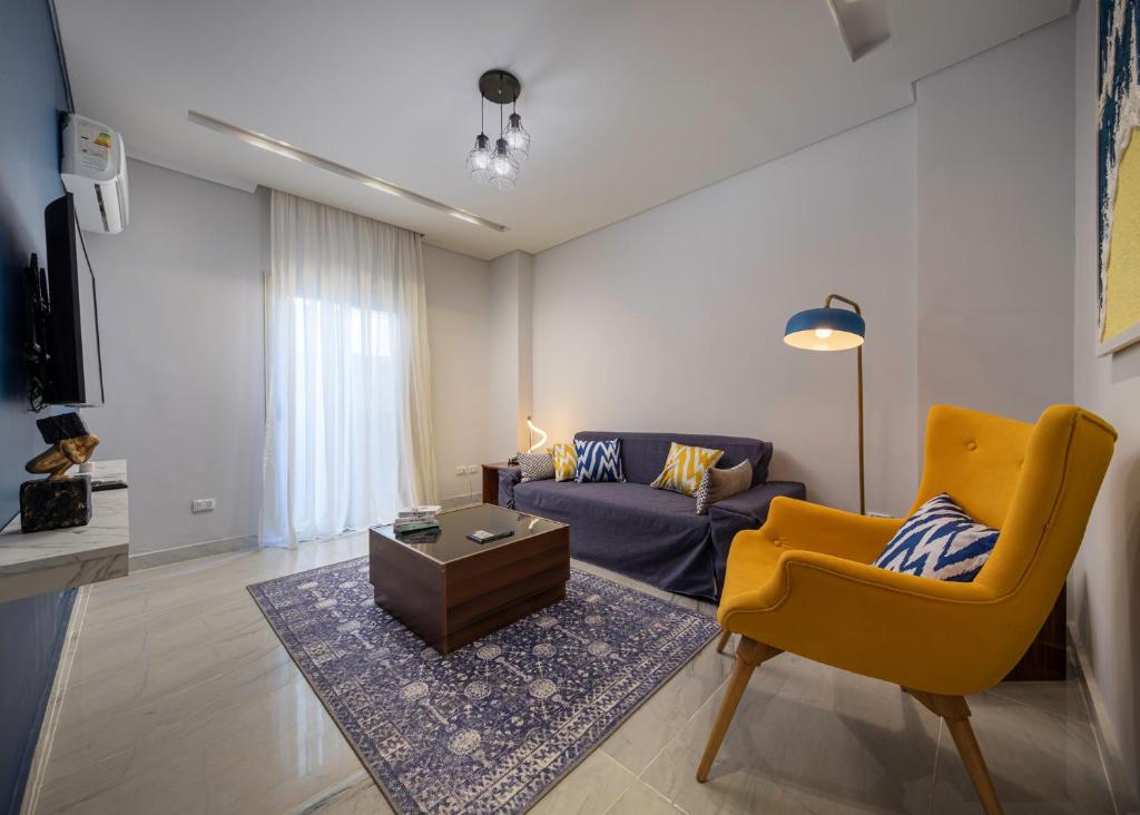un salon avec un canapé et une chaise jaune dans l'établissement Travelholic 90 Residence, au Caire