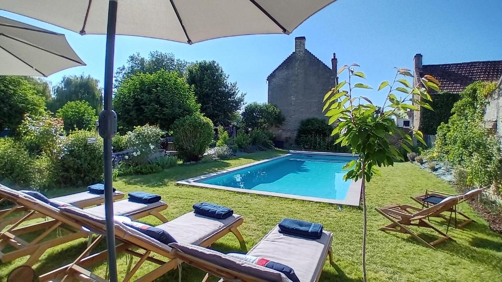 einen Pool mit zwei Liegestühlen und einem Sonnenschirm in der Unterkunft Le Clos de l'Aiguillon 