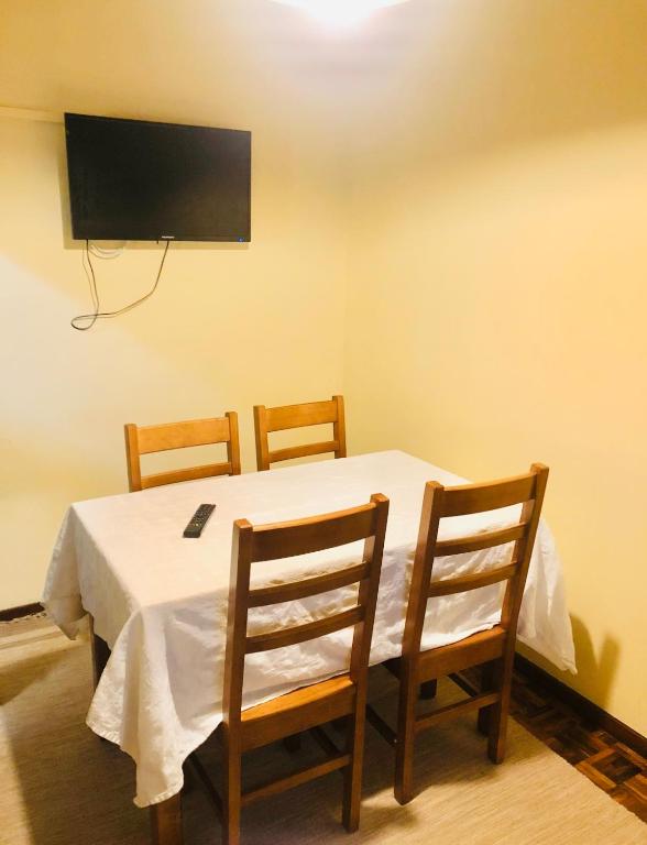 a table with three chairs and a television on a wall at Cantinho da Glória in Aveiro