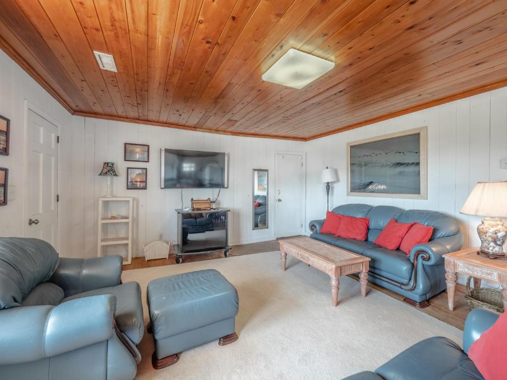 a living room with blue furniture and a wooden ceiling at Sunrise in Topsail Beach