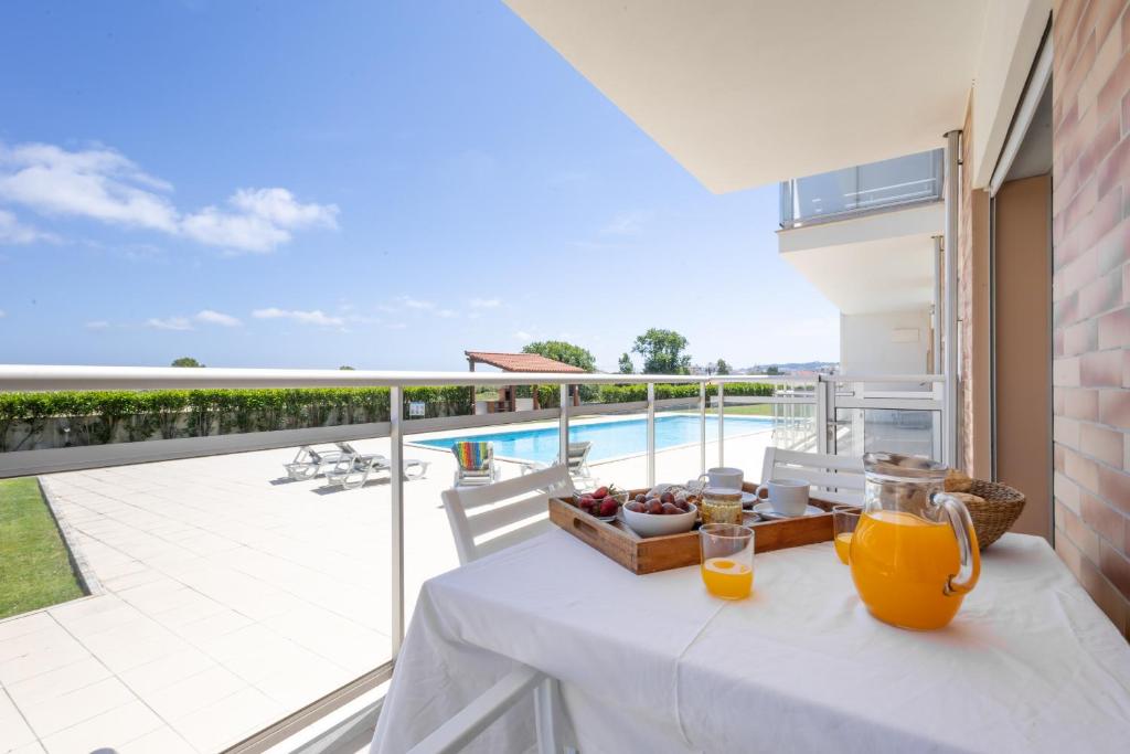 uma mesa com uma tigela de fruta e sumo de laranja na varanda em Carmona A T2 - By Smarthomes em São Martinho do Porto