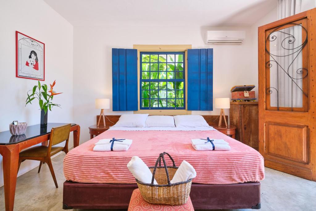 1 dormitorio con cama, escritorio y ventana en Pousada Pontal Gardens en Parati