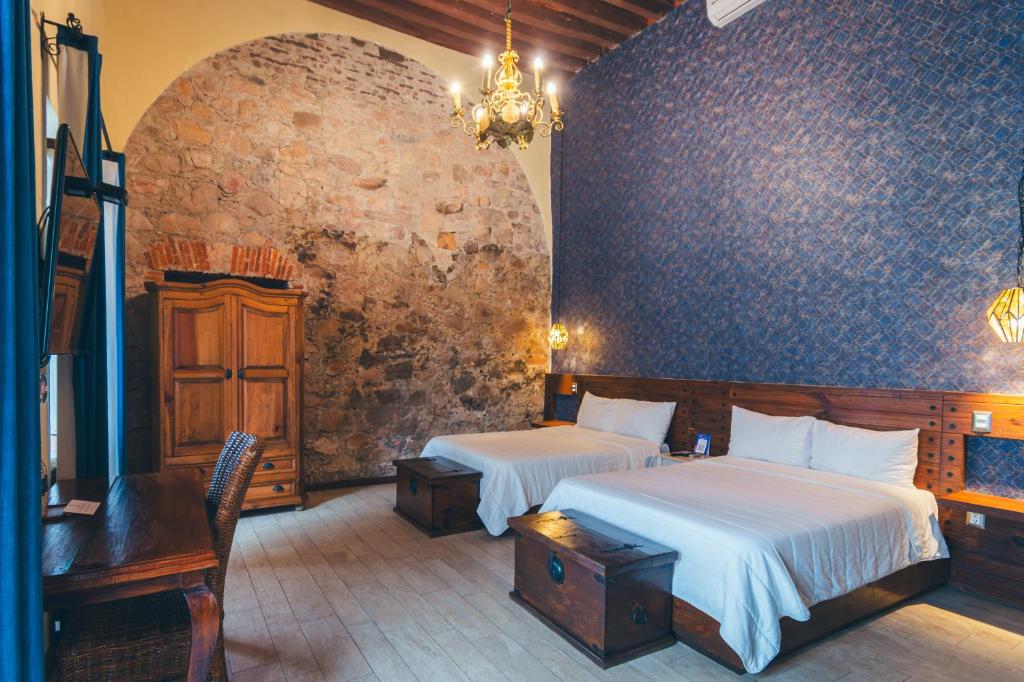 a bedroom with two beds in a room with a wall at Hotel Boutique Casa Altamira in Querétaro