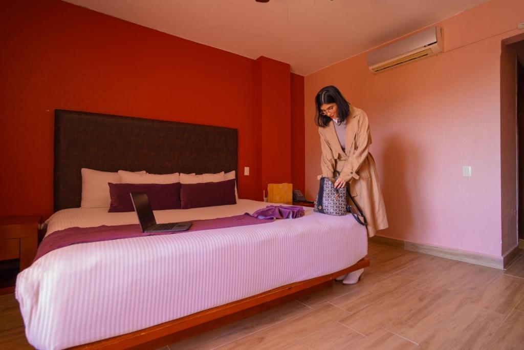 瓜納華托的住宿－Hotel Suites Corazón Mexicano，站在房间床边的女人