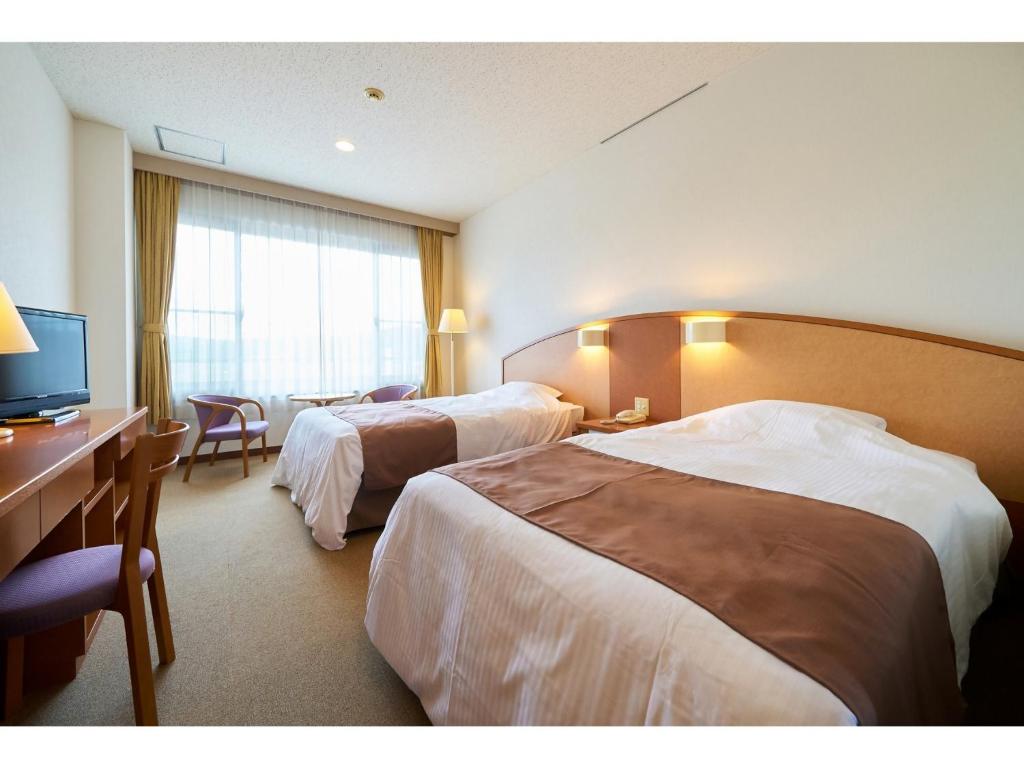 a hotel room with two beds and a desk and a television at Sunroad Kibiji - Vacation STAY 05992v in Soja