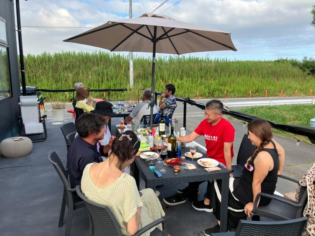a group of people sitting around a table with an umbrella at Bonfire Beach Club - Vacation STAY 06134v in Katakai