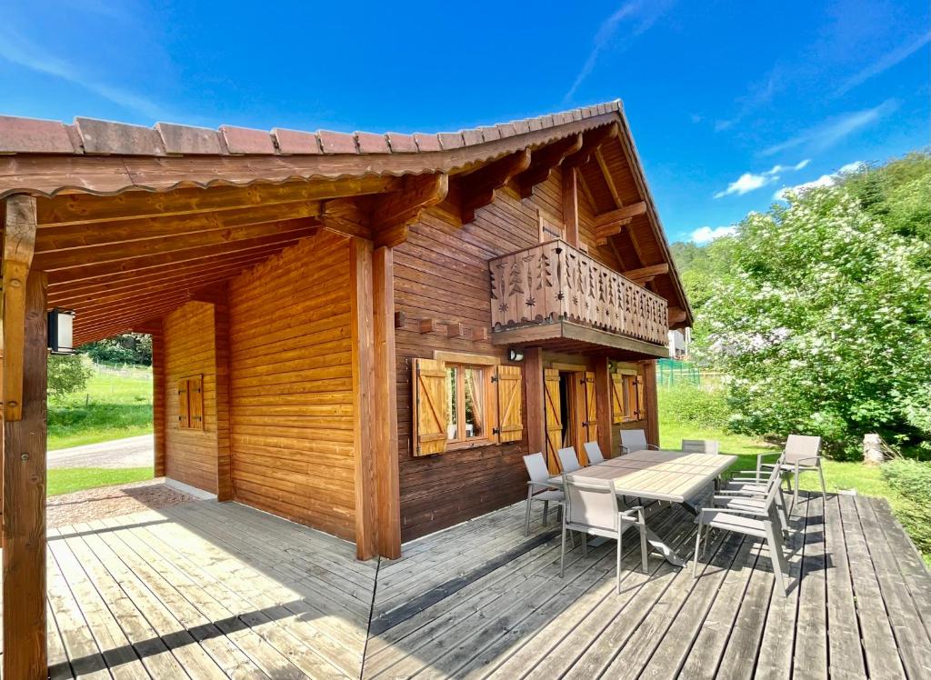 une terrasse en bois avec une table et des chaises dessus dans l'établissement Chalet Le Chappoix, 4* avec grand jardin, à Granges-sur-Vologne