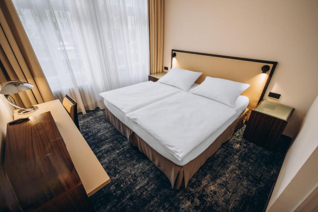 a bedroom with a bed with white sheets and pillows at Esplanade Carlsbad in Karlovy Vary