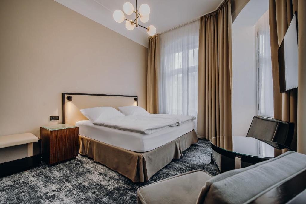a hotel room with a bed and a chair at Esplanade Carlsbad in Karlovy Vary