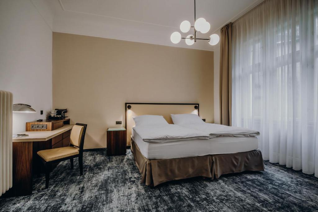 a bedroom with a bed and a desk and a table and a bed at Esplanade Carlsbad in Karlovy Vary