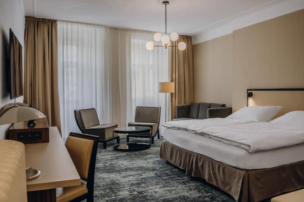 a hotel room with a large bed and chairs at Esplanade Carlsbad in Karlovy Vary