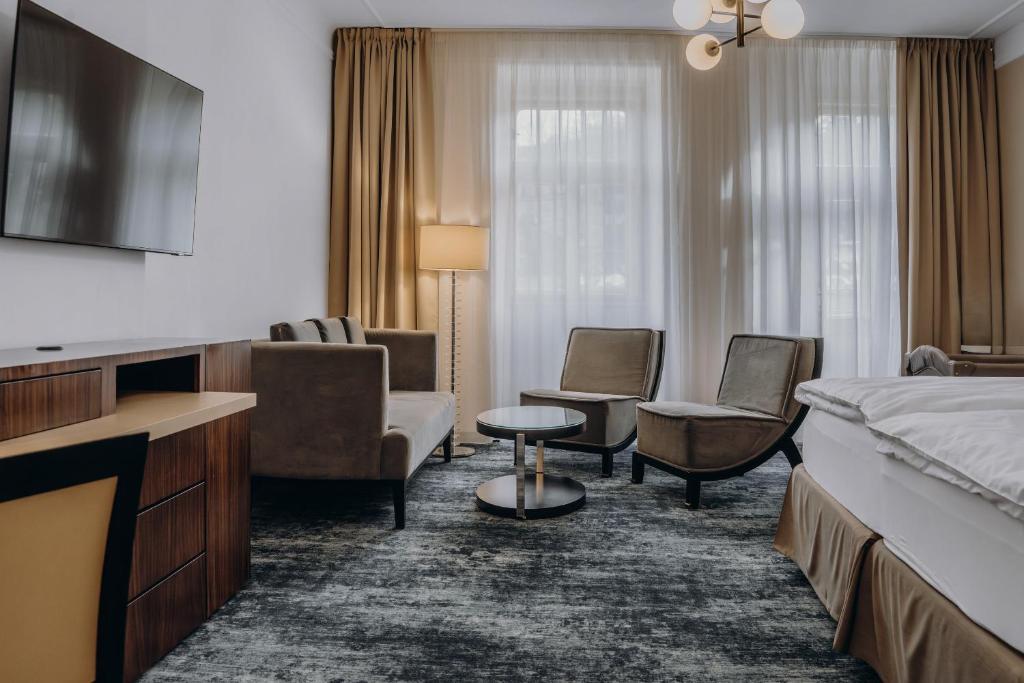 a hotel room with a bed and a couch and chairs at Esplanade Carlsbad in Karlovy Vary