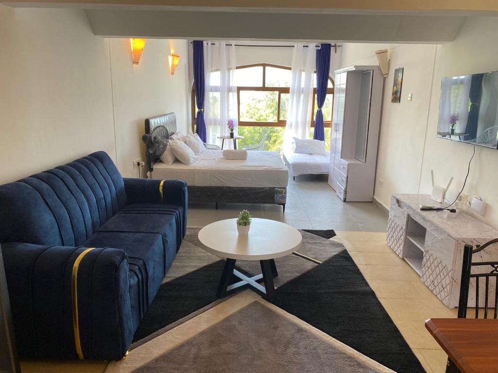 a living room with a blue couch and a bed at Seabreeze suites Villa in Diani Beach
