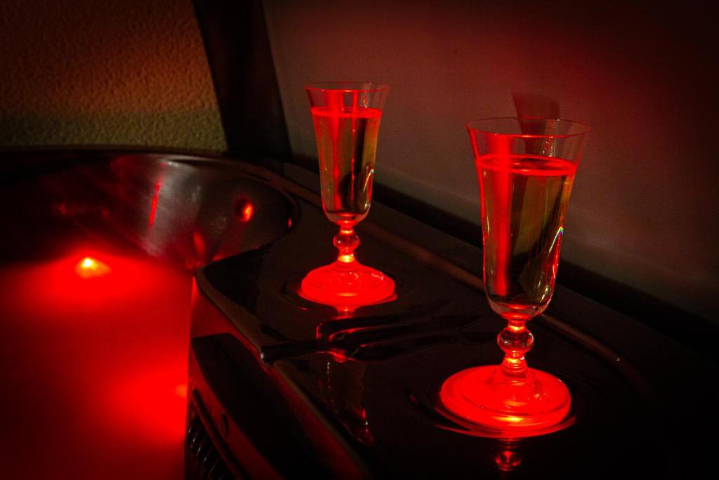 two red glasses sitting on a table with a candle at Prestige De Cocagne in Lavaur
