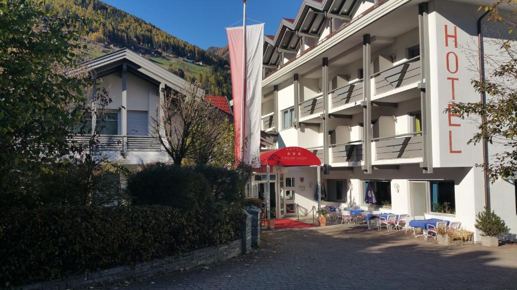 um hotel com um guarda-chuva vermelho ao lado de um edifício em Hotel Tiroler Adler em Lutago