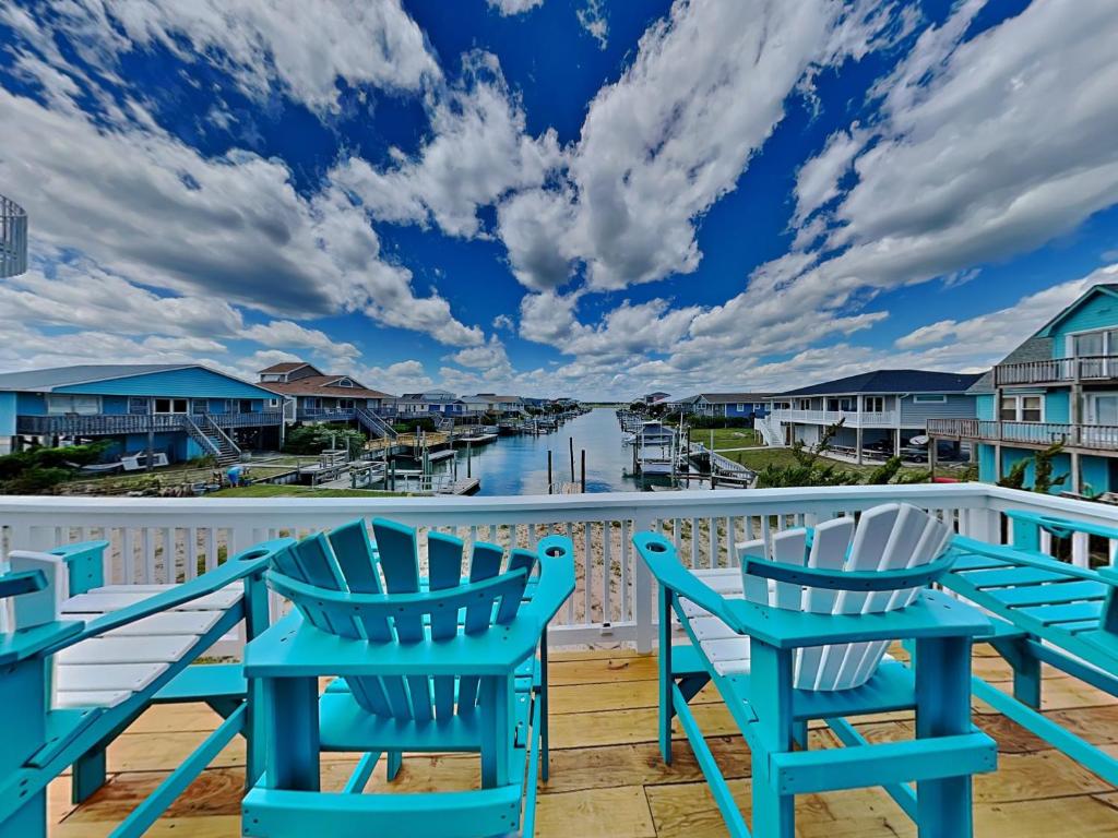 a deck with chairs and a view of a marina at The Last Dollar Cottage in Topsail Beach