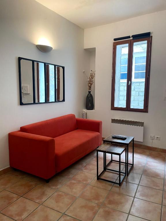 un salon avec un canapé rouge et une table dans l'établissement Appartement Avignon intra-muros, à Avignon