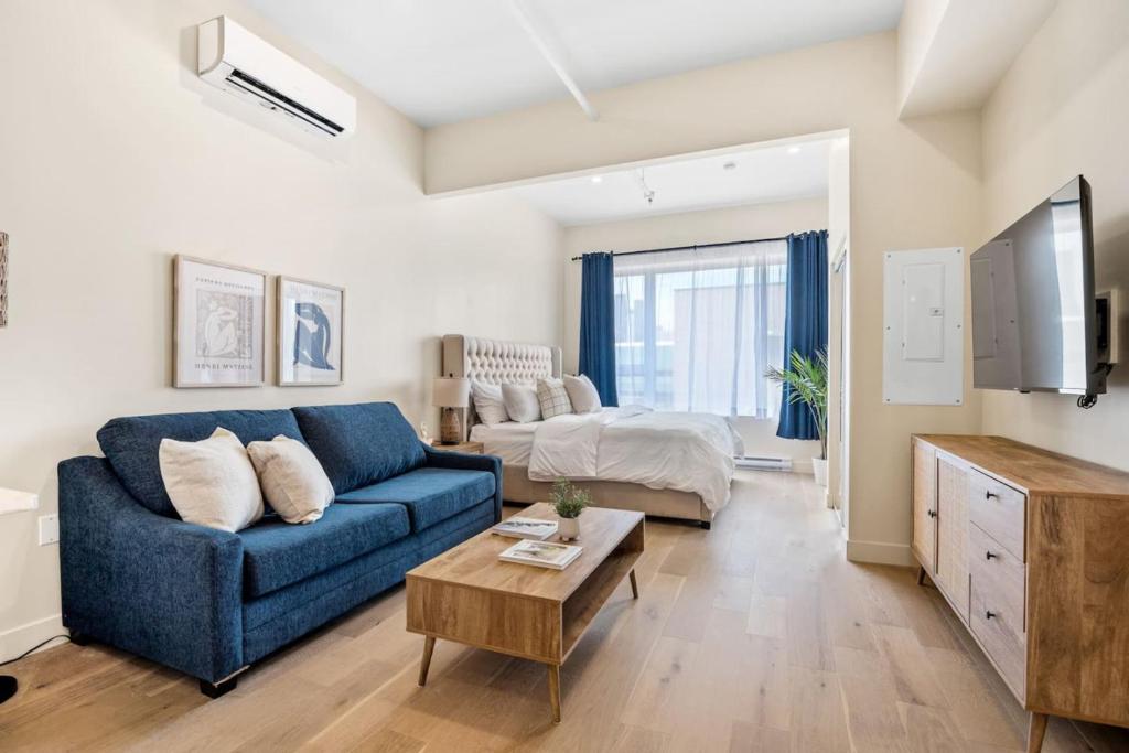 a living room with a blue couch and a bed at Central King Studio in Montreal
