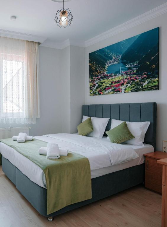 a bedroom with a large bed with a painting on the wall at Downtown Bayrak Residences Trabzon in Trabzon