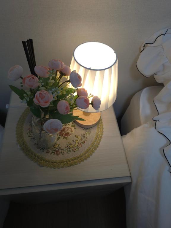 a table with a lamp and a vase of flowers on it at HaengBok in Seoul