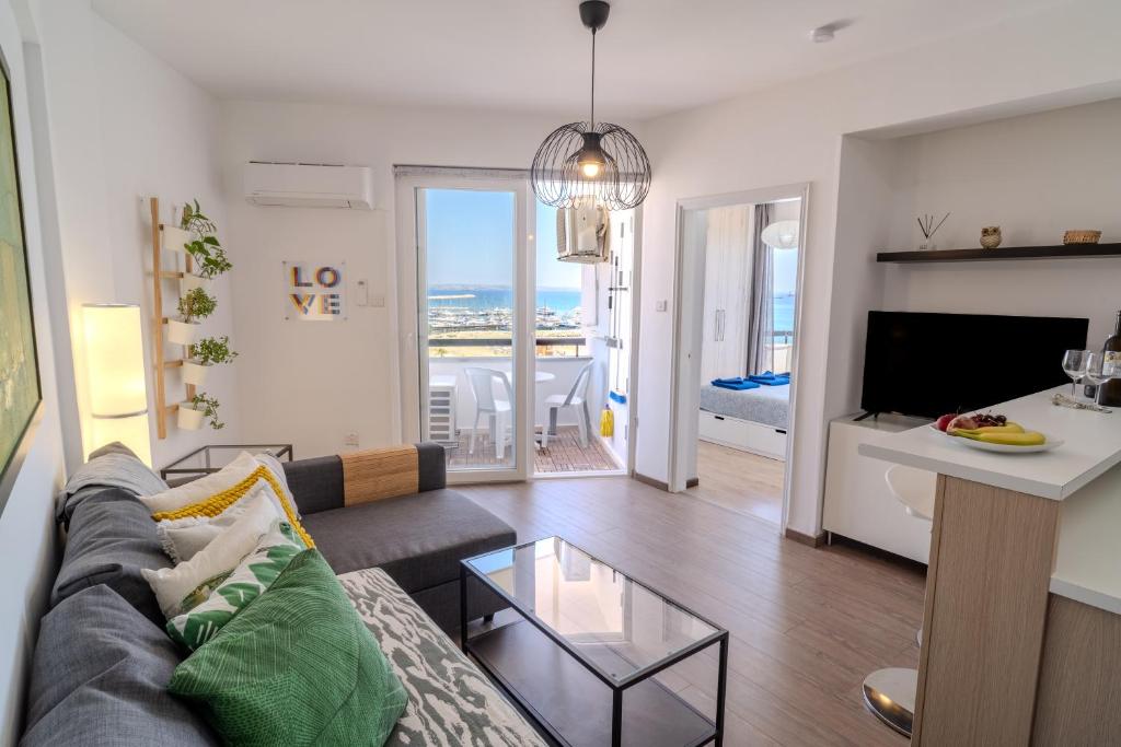 a living room with a couch and a table at Finikoudes Seaview Vibe 1 Bdr Flat in Larnaka