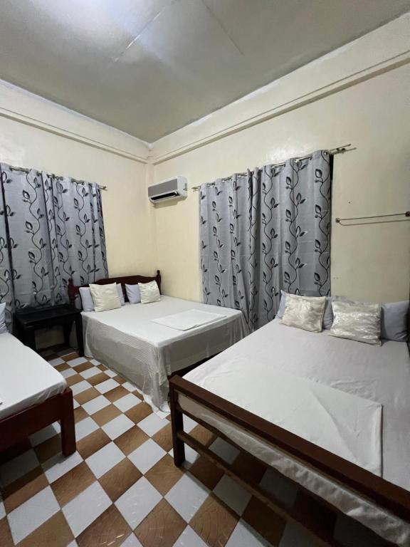 a room with two beds and a checkered floor at Besañes Homestay in Alaminos
