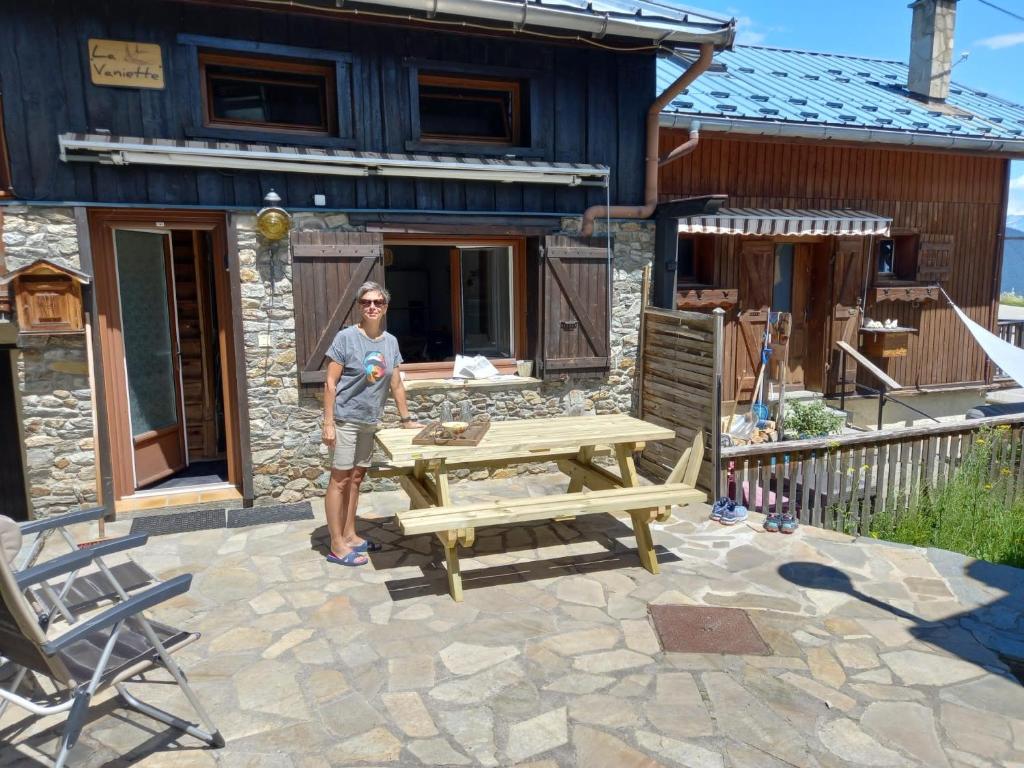 un homme debout à côté d'une table de pique-nique devant une maison dans l'établissement Chalet de montagne au cœur de Doucy, à Doucy