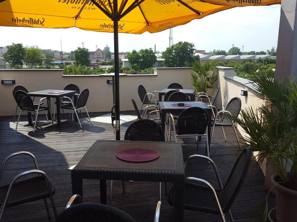 a patio with tables and chairs and an umbrella at Stadt-gut-Hotel Westfalia in Halle an der Saale