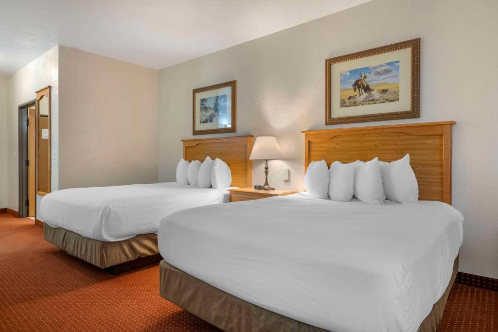 two beds in a hotel room with white sheets at Best Western Devils Tower Inn in Hulett