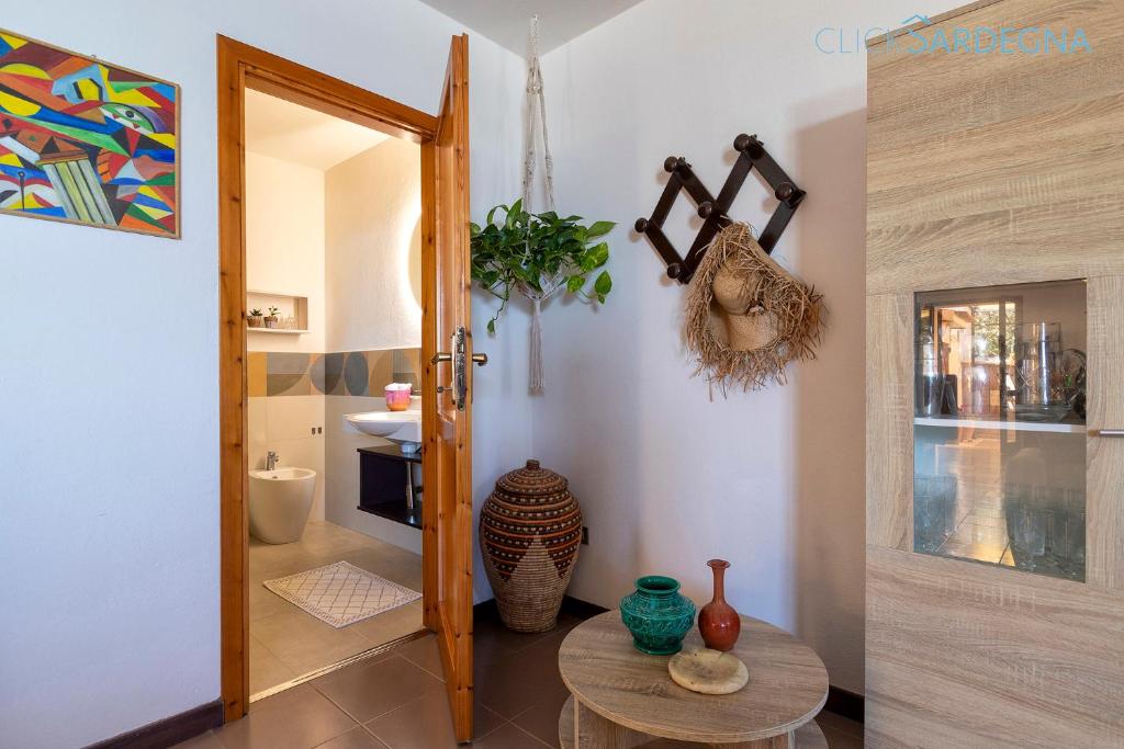 Cette chambre dispose d'une table et d'une porte avec des vases. dans l'établissement Villa Joie de Vivre Vista mare con piscina a sfioro per 6 persone, à Alghero
