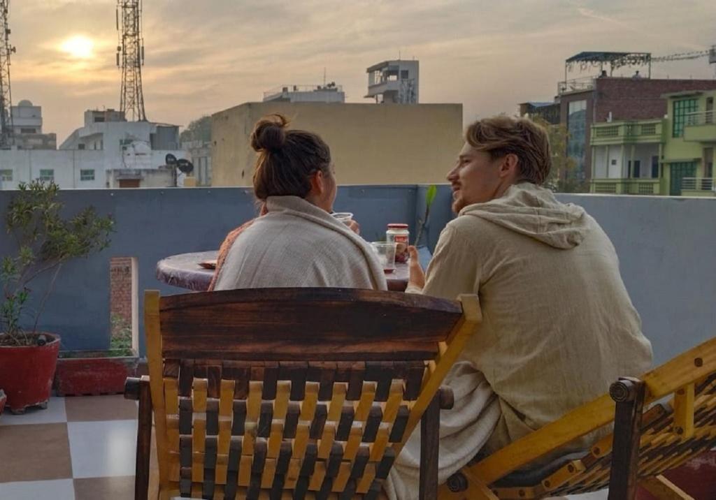 two women sitting on a bench on a roof at Taj Street Hostel in Agra