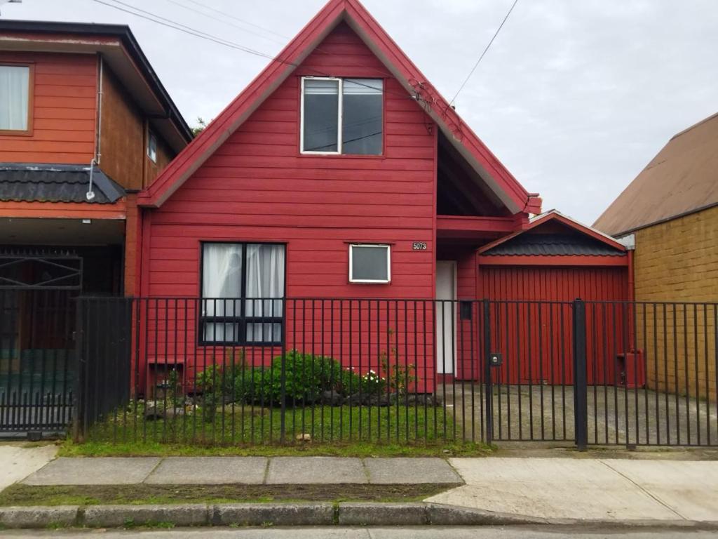 a red house with a fence in front of it at Casa Valle Volcanes 3 Dormitorios in Puerto Montt
