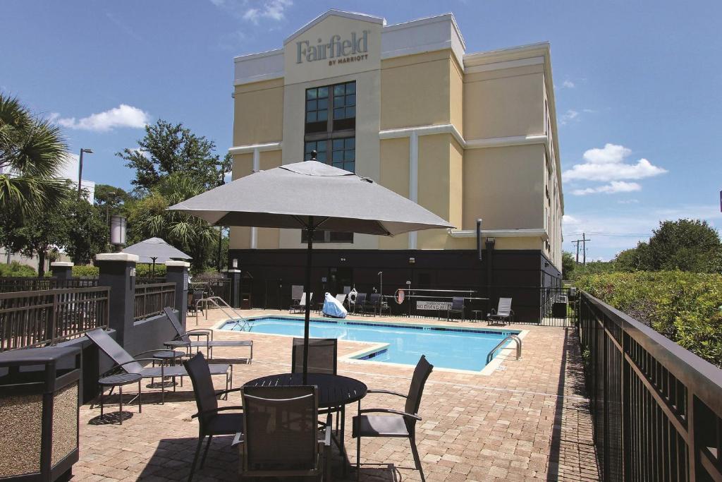 hotel z basenem, krzesłami i parasolem w obiekcie Fairfield Inn & Suites by Marriott Charleston Airport/Convention Center w mieście Charleston