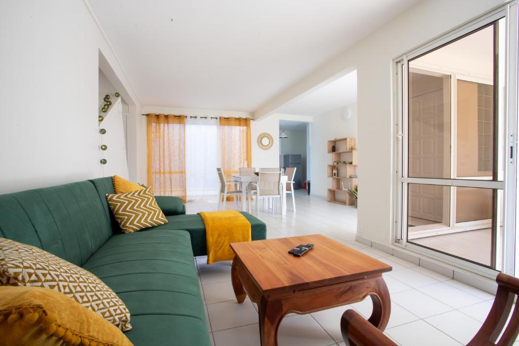a living room with a green couch and a table at Appartement les pieds dans l'eau in Sainte-Anne