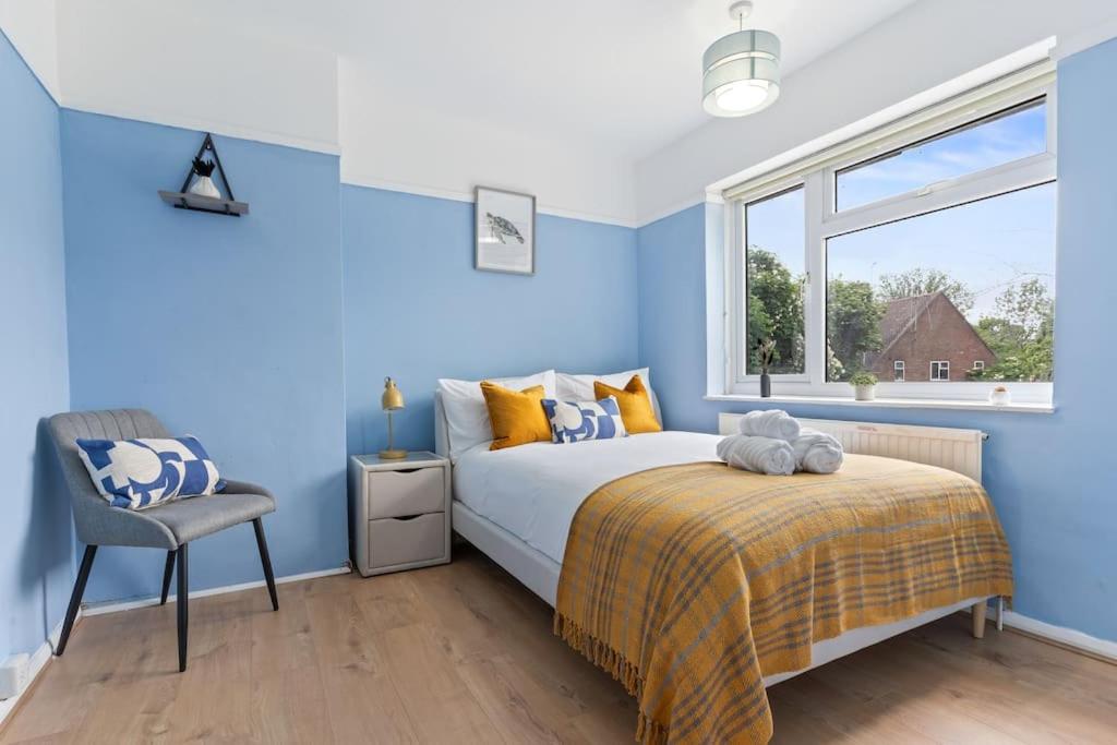 a blue bedroom with a bed and a chair at Beautiful 5 Bedroom House in Aylesbury free Parking PENN ROAD in Buckinghamshire