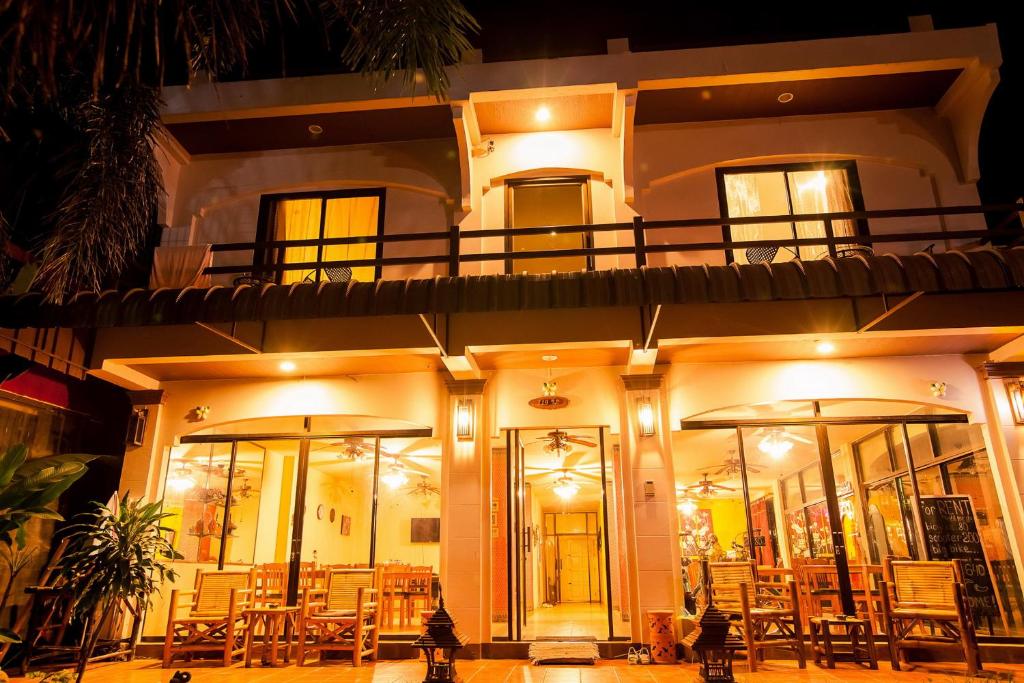 een gebouw met tafels en stoelen er 's nachts voor bij Klong Muang Sunset House in Klong Muang Beach