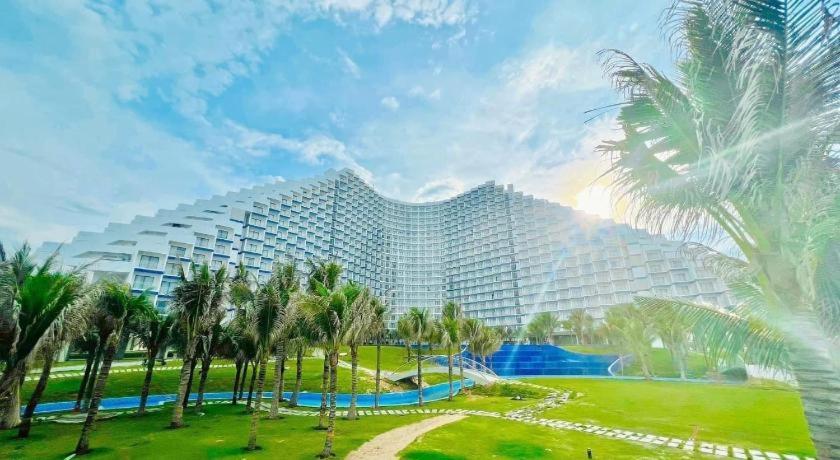 a large building with palm trees in front of it at Happy Beach Seaview Condotel at The Arena Cam Ranh Resort in Cam Ranh