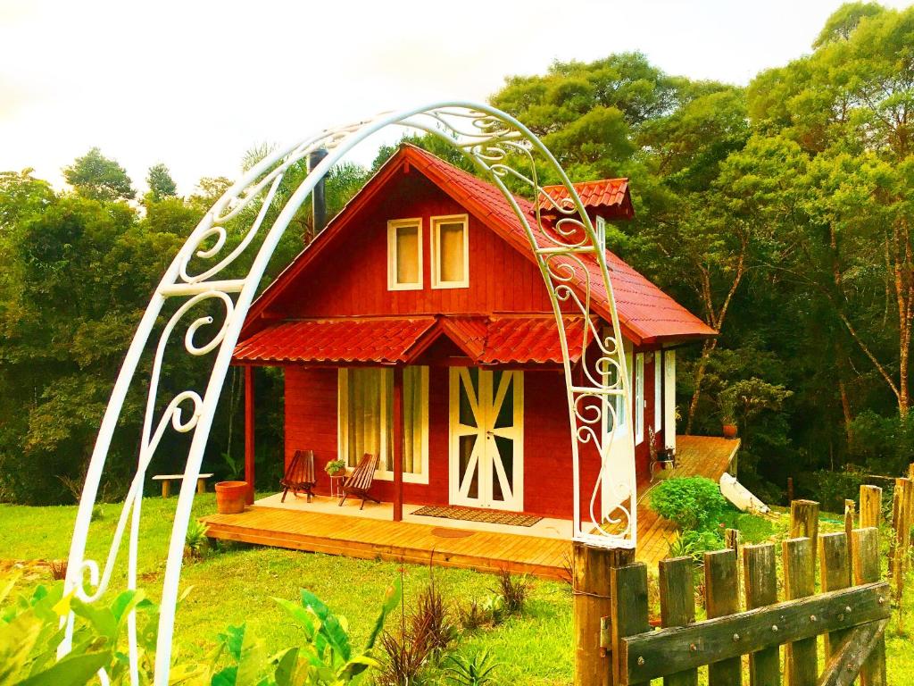 a small red house in a yard with a gate at Cabanas dos Sonhos na Serra SC in Rancho Queimado