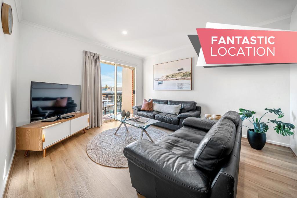 un salon avec un canapé en cuir noir et une télévision dans l'établissement In The Midst on Melbourne, à Adélaïde