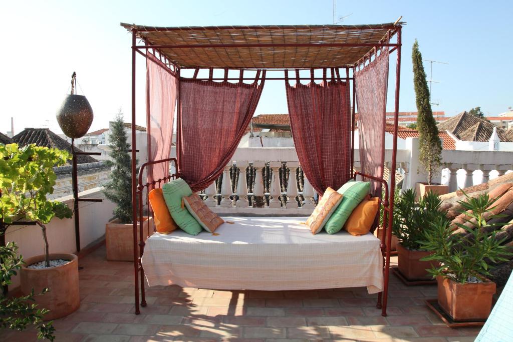 a canopy bed on a balcony with plants at Casa Beleza do Sul in Tavira