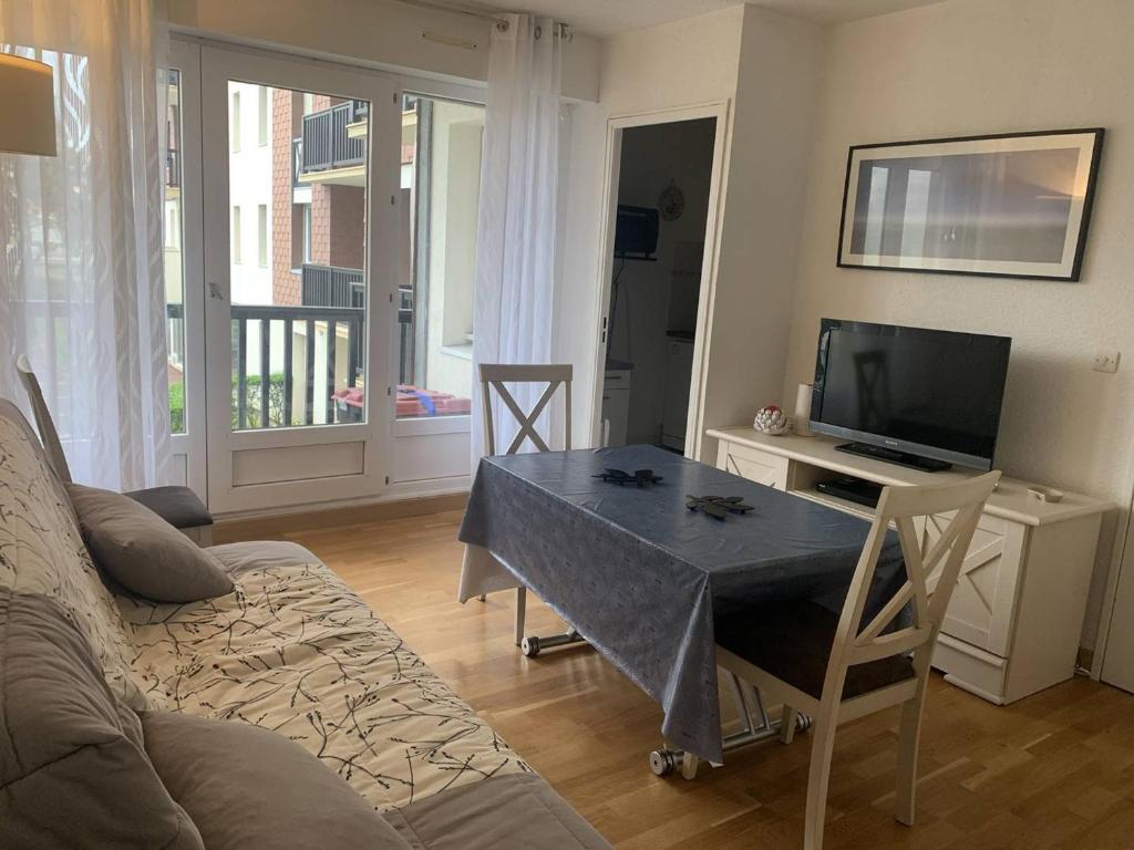 un salon avec un canapé, une table et une télévision dans l'établissement Appartement lumineux à 50m de la plage de Cabourg, balcon, parking gratuit, 4 pers. - FR-1-465-119, à Cabourg