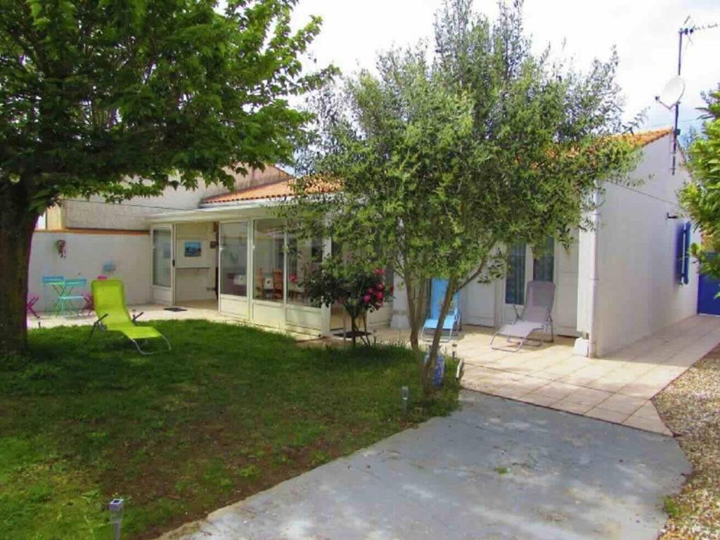 een huis met een tuin met een groene stoel bij Maison 4 pièces près plage - Saint-Denis-d'Oléron, 6 couchages - FR-1-246A-309 in Saint-Denis-dʼOléron