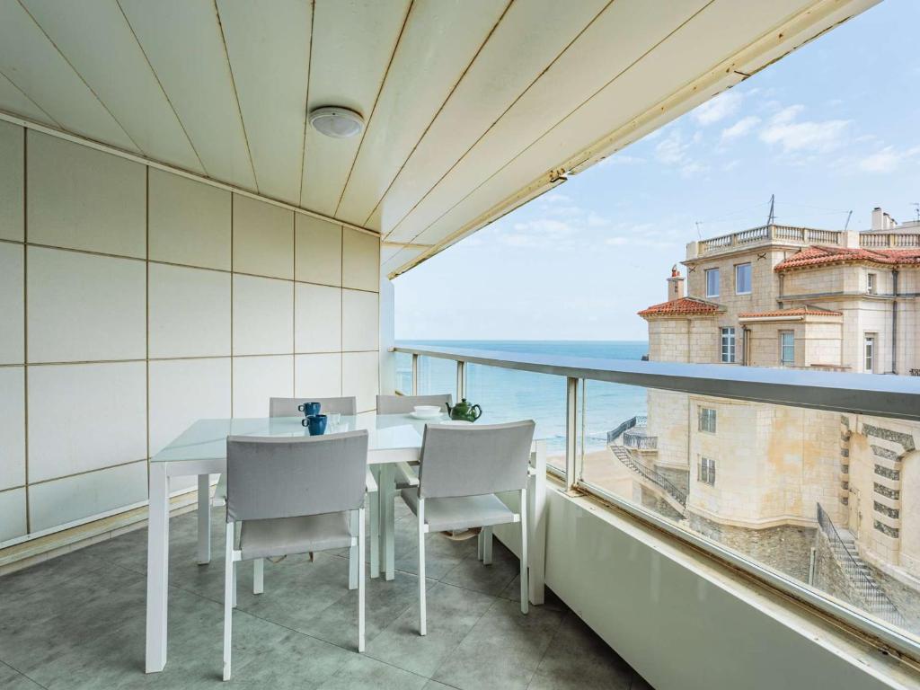 une salle à manger avec une table et des chaises sur un balcon dans l'établissement Studio moderne en bord de mer avec accès piscine à Biarritz - FR-1-3-611, à Biarritz